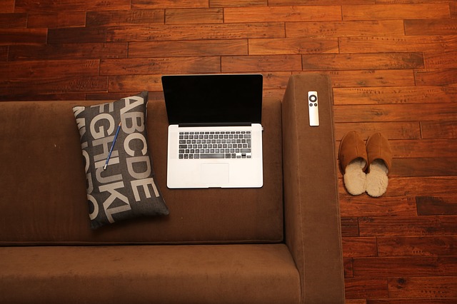 Overhead shot of laptop setting on couch on beautiful hardwood floor.