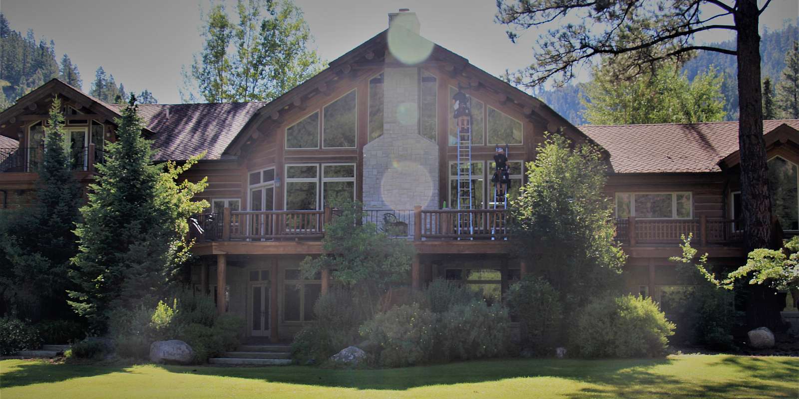 Purity Montana window cleaners cleaning front windows of a beautiful log cabin