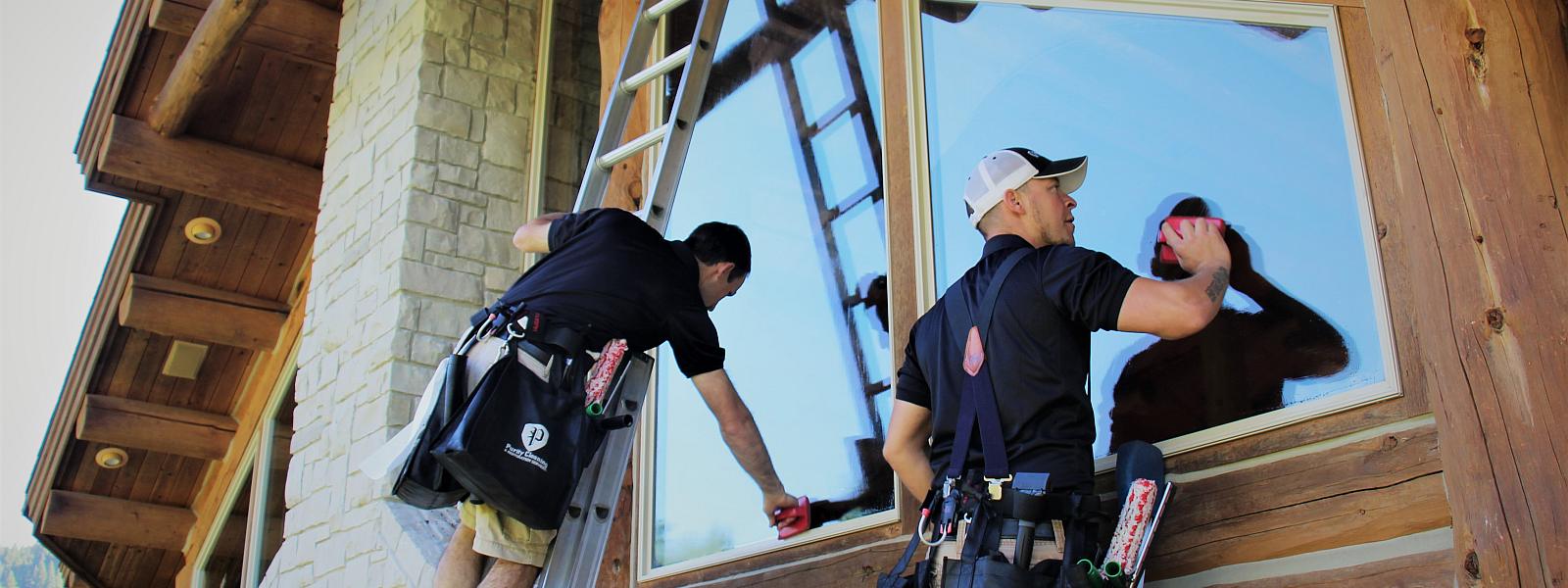 Purity Cleaning team washing exterior windows on a log cabin in Bitterroot Valley Mt